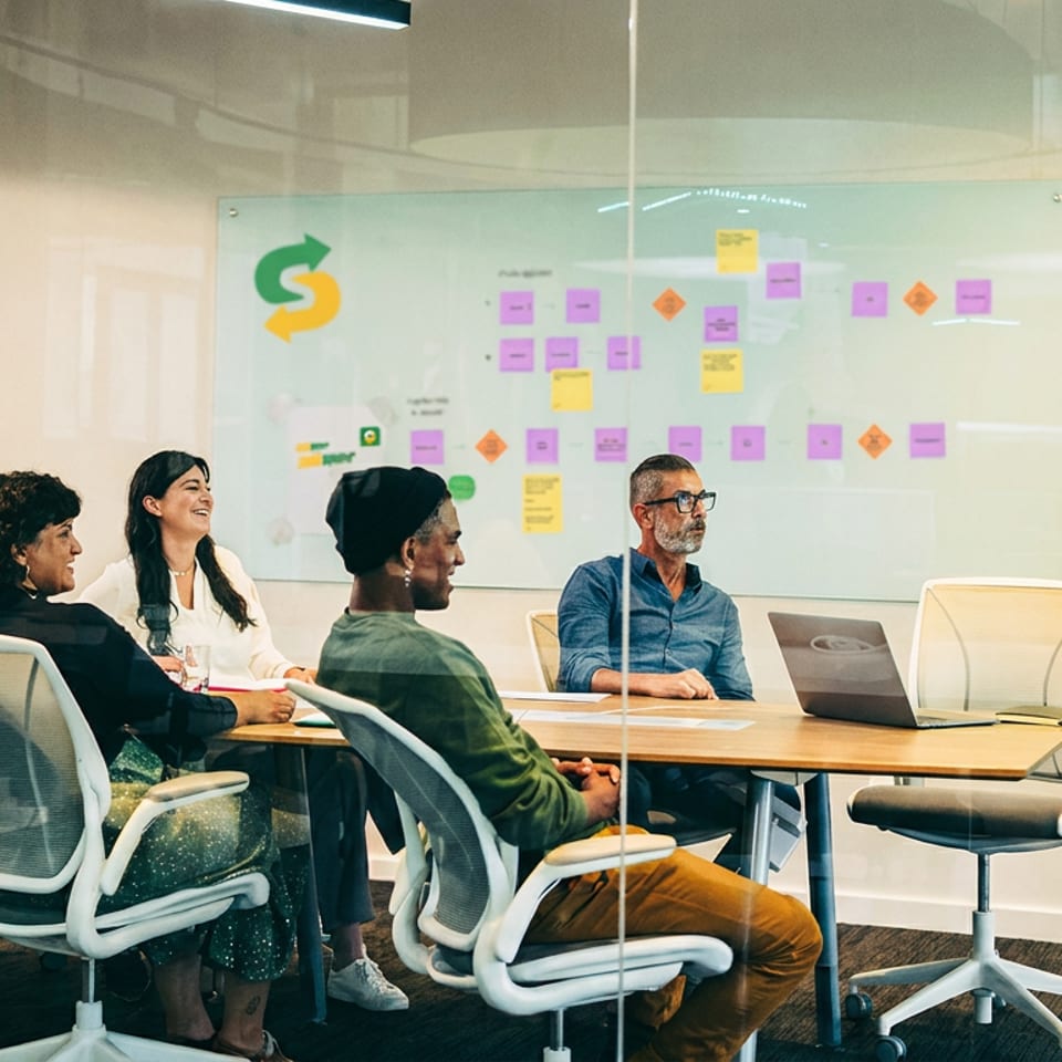 Diverse team meeting in a modern conference room with a presenter and a whiteboard showing the Subway logo.