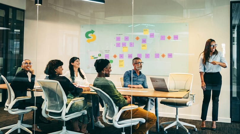 Diverse team meeting in a modern conference room with a presenter and a whiteboard showing the Subway logo.
